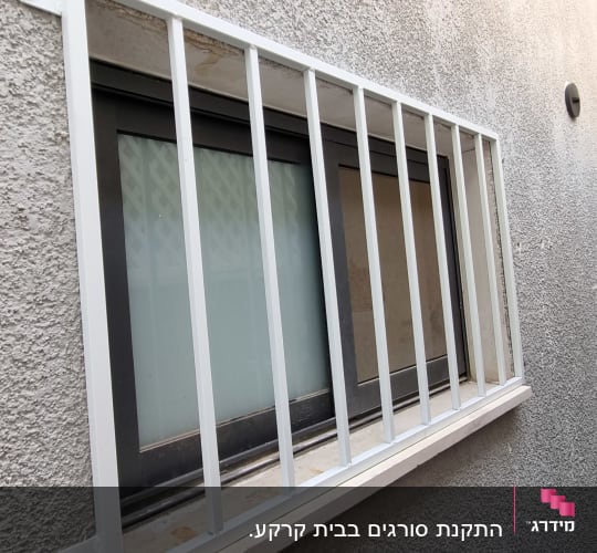 סורגי מתכת לבנים על חלון קיר חיצוני